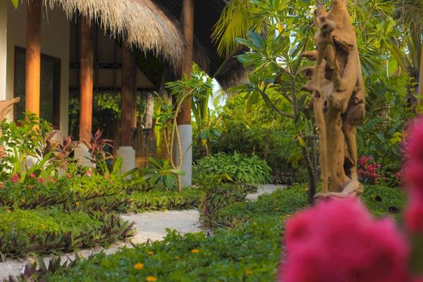 Gartenbereich des Fushifaru Maldives Hotels mit Gehweg und Pflanzen.
