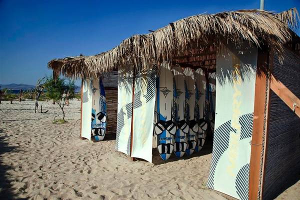 Mehrere Surfbretter sind unter einem Strohdach im Atlantica Marmari Beach Hotel aufgestellt.