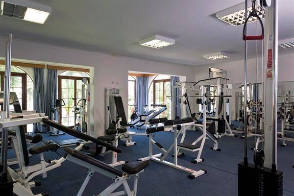 Fitnessstudio im Atlantica Marmari Beach Hotel mit verschiedenen Geräten und blauem Boden.