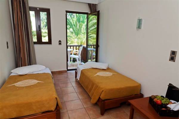 Zimmer mit zwei Betten und Balkon mit Blick auf den Garten im Atlantica Marmari Beach Hotel.