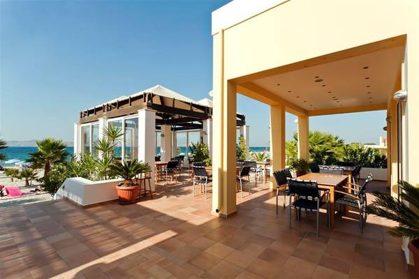 Terrasse des Atlantica Marmari Beach Hotels mit Tischen, Stühlen und Pflanzen.