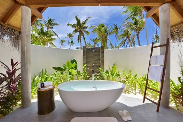 Außenbadewanne im Fushifaru Maldives Hotel mit Blick auf Palmen und blauen Himmel