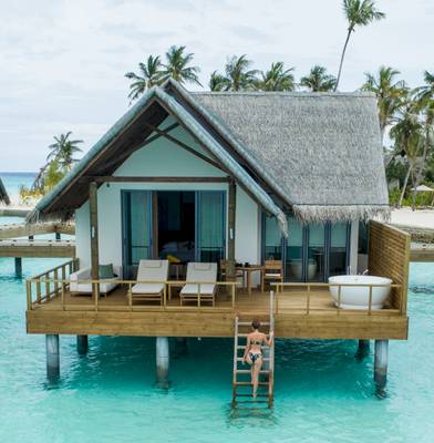Wasservilla im Fushifaru Maldives mit Frau auf Leiter.