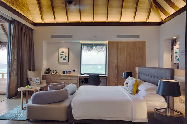 Schlafzimmer im Fushifaru Maldives Hotel mit Blick auf das Meer.