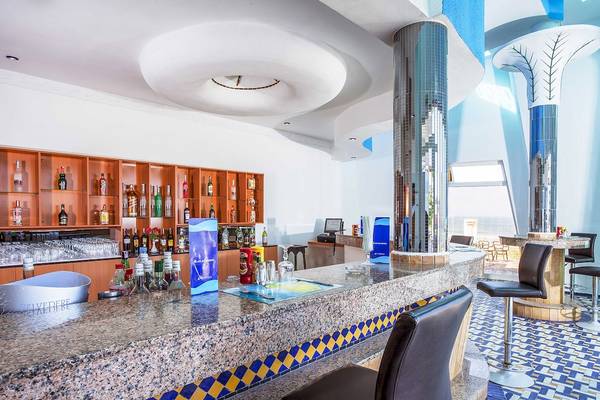Die Bar im Atlas Amadil Beach Hotel mit Granittheke und blau-gelbem Bodenmuster.