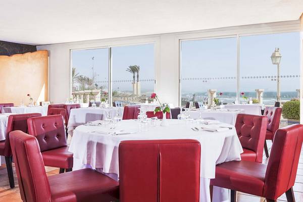Innenansicht des Restaurants im Atlas Amadil Beach Hotel mit Blick auf das Meer und roten Stühlen.