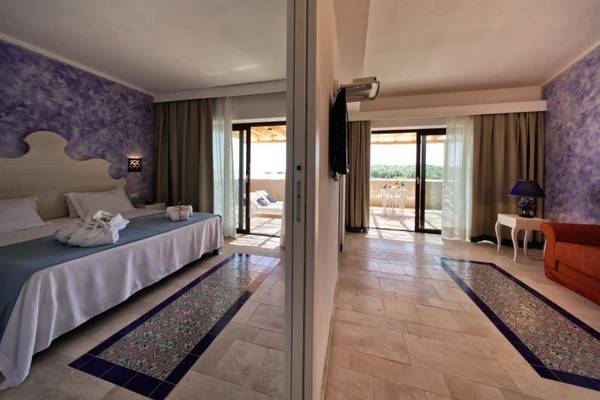 Schlafzimmer im Baglioni Resort Sardinia mit Balkon, doppeltem Bett und Terrassenmöbeln