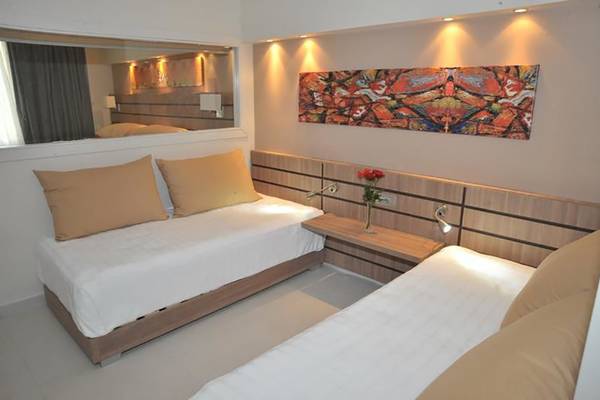 Doppelbettzimmer im Atlantica Holiday Village Kos mit modernen Möbeln und Kunstwerk an der Wand.