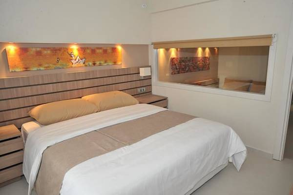 Ein Schlafzimmer im Atlantica Holiday Village Kos mit einem Bett, zwei Nachttischen und einem großen Fenster.