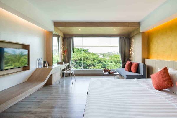 Innenansicht eines Zimmers im Chaba Samui Resort mit großem Bett, Fernseher und Schreibtisch.