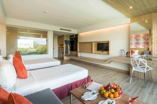 Ein elegantes Hotelzimmer im Chaba Samui Resort mit zwei Betten, einem Tisch mit Früchten und einer Aussicht auf den Garten.