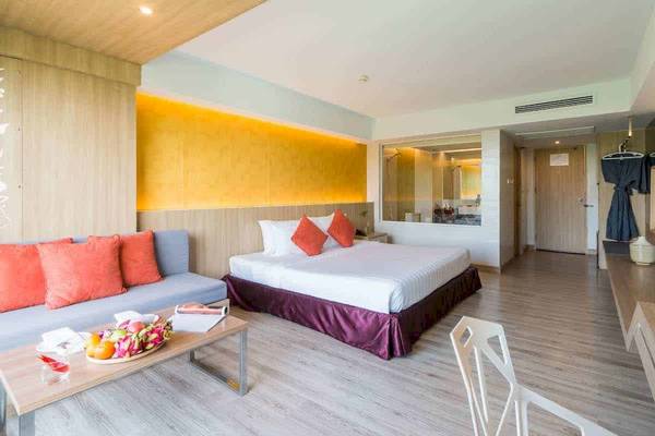 Hotelzimmer im Chaba Samui Resort mit einem Bett, einem Sofa und einem Tisch mit Früchten.