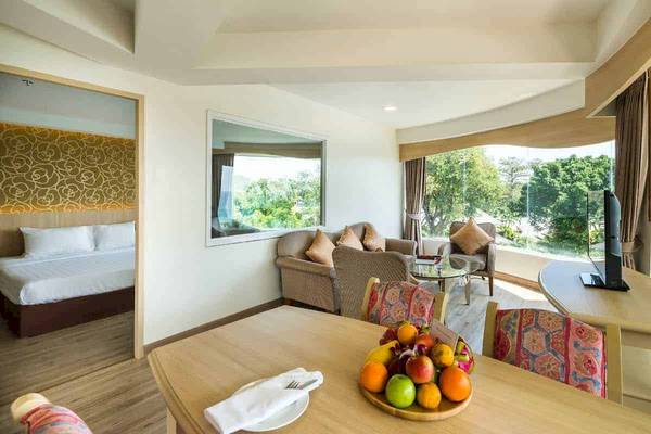 Innenansicht des Chaba Samui Resort Hotelzimmers mit Esstisch, Obst, Fernseher und Fenstern.