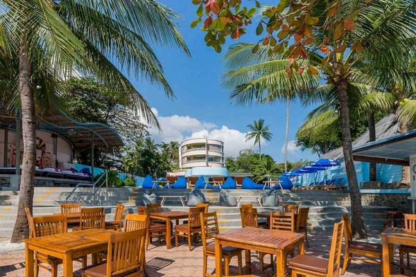 Außenbereich des Chaba Samui Resorts mit blauen Sonnenschirmen und Holztischen.
