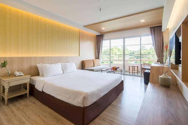 Innenansicht eines Hotelzimmers im Chaba Samui Resort mit einem Bett, Nachttischen und einem Fernseher.