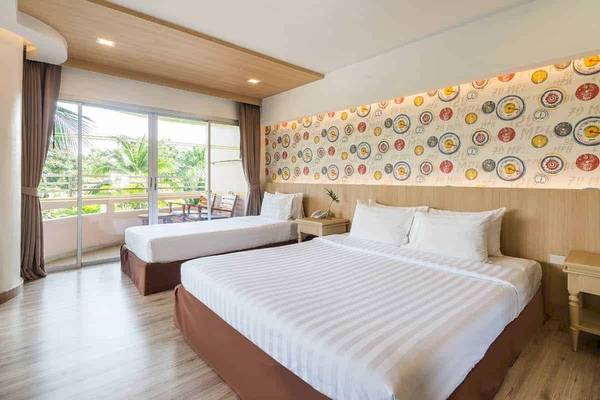 Innenansicht eines Doppelzimmers im Chaba Samui Resort mit zwei Betten, Nachttischen und einer Wand mit bunten Kreismustern.
