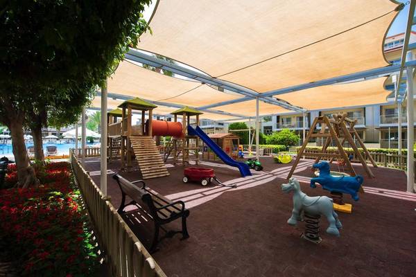 Kinderspielplatz im Barut B Suites Hotel mit Rutsche, Schaukel und Blumen.