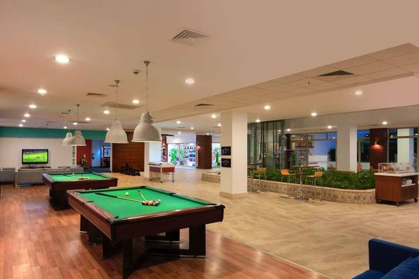 Poolbereich im Barut B Suites Hotel mit zwei Billardtischen, Sofas und Fernseher.