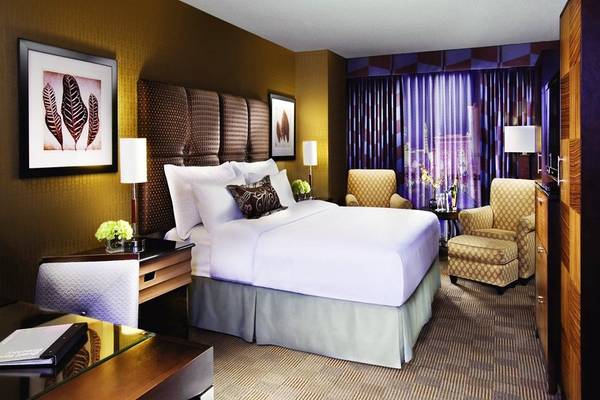 Schlafzimmer im New York-New York Hotel & Casino mit großem Bett, Sesseln und Dekor.