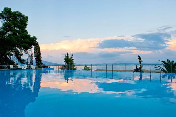 Außenansicht des Pools im Kontokali Bay Resort & Spa mit umliegenden Bäumen und Sonnenuntergang.