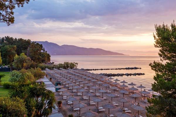 Strand mit Sonnenliegen am Kontokali Bay Resort & Spa während des Sonnenuntergangs.