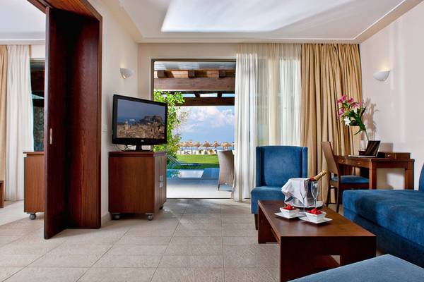 Hotelzimmer mit Fernseher, Couch, Tisch, und Aussicht auf den Pool.