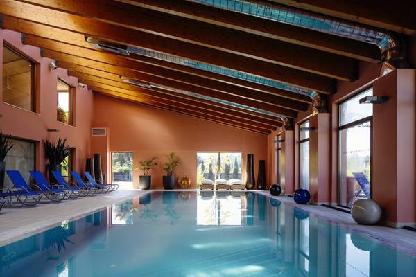 Innenpool des Kontokali Bay Resort & Spa mit Loungebereich und Holzdecken.