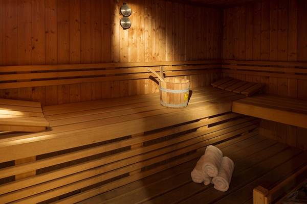 Eine geräumige, helle Sauna im Hotel Kontokali Bay Resort & Spa mit Holzbänken und einem Eimer.
