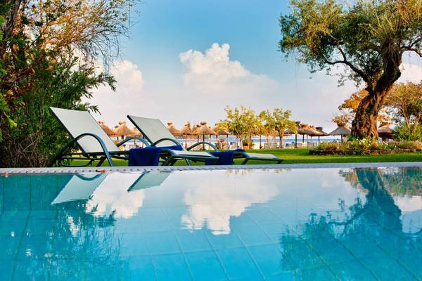 Pool mit Liegestühlen und Blick auf das Meer im Kontokali Bay Resort & Spa