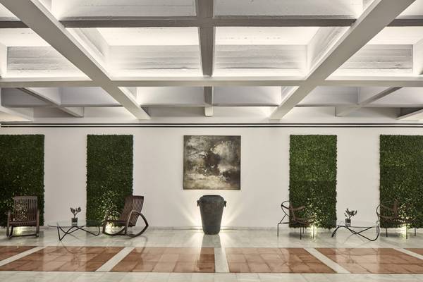 Lobby des Kontokali Bay Resort & Spa mit weißen Wänden, grünen Pflanzenwänden und modernen Möbeln.