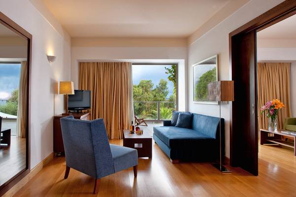 Wohnzimmer im Kontokali Bay Resort & Spa mit Sofa, Fernseher und Glasfenster mit Aussicht.