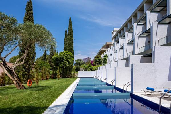 Außenpool des Kontokali Bay Resort & Spa mit weißen Wänden und grünem Rasen