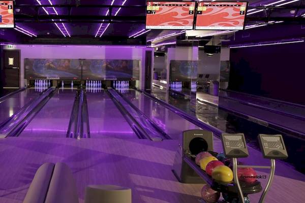 Kempinski Hotel Muscat Bowlinghalle mit Bowlingbahnen und lila Beleuchtung.