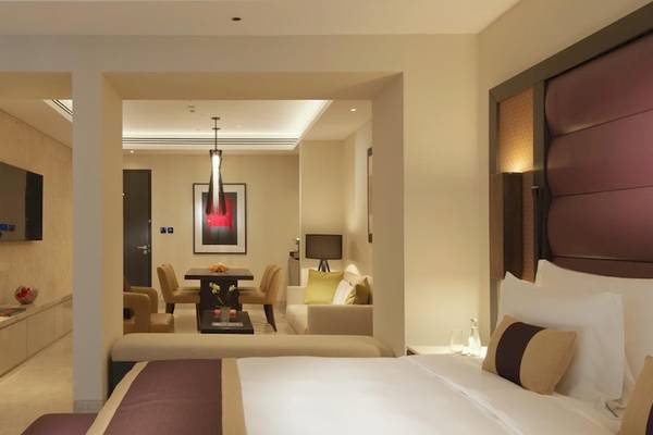 Innenansicht einer Suite im Kempinski Hotel Muscat mit Bett, Wohnzimmer und Essbereich.