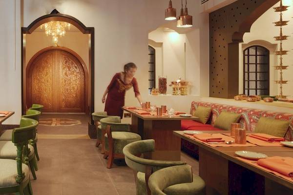 Innenansicht des Restaurants im Kempinski Hotel Muscat mit einer Bedienung, die die Tische vorbereitet.