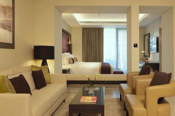 Innenansicht der Suite im Kempinski Hotel Muscat mit Wohnzimmer, Schlafbereich und Fernseher.