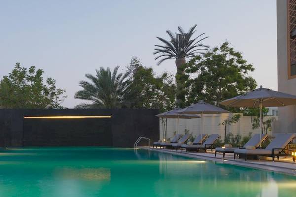 Pool-Loungebereich des Kempinski Hotels Muscat mit Sonnenliegen und Schirmen.