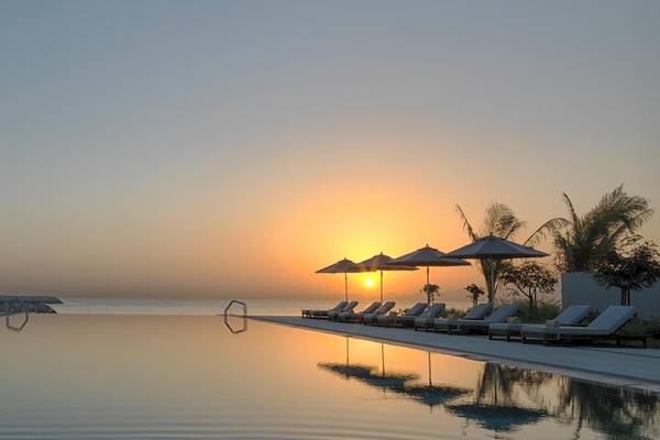 Sonnenuntergang am Pool des Kempinski Hotels in Muscat mit Liegestühlen und Sonnenschirmen