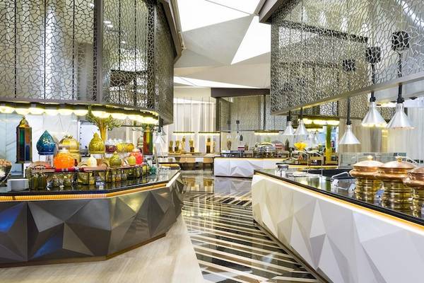 Innenbereich des Restaurants im Kempinski Hotel Muscat mit modernen Möbeln und einer langen Theke mit verschiedenen Speisen.