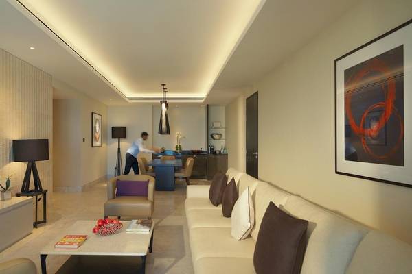 Wohnbereich im Kempinski Hotel Muscat mit Möbeln, Fernseher und Kunstwerk an der Wand.