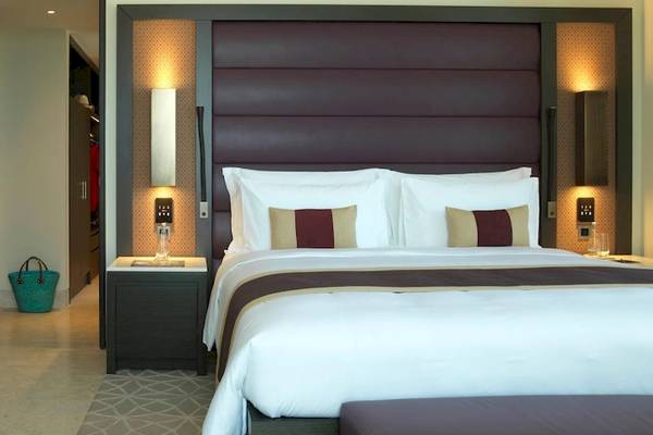 Schlafzimmer im Kempinski Hotel Muscat mit einem großen Bett, Kissen und Nachttischen.