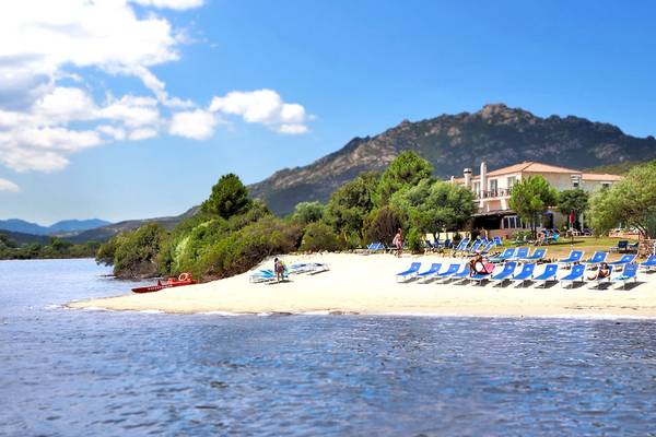 Strand mit blauen Liegestühlen und einem Hotel im Hintergrund.