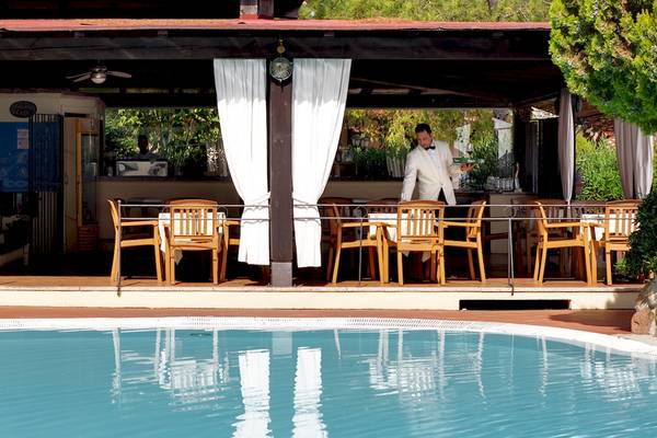 Ein Butler serviert im Freien am Poolbereich des Colonna Hotel Du Golf.
