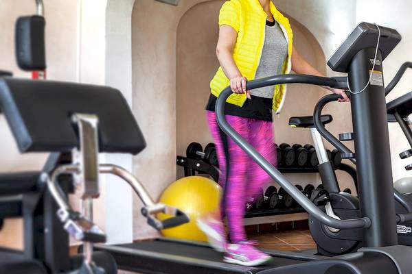 Frau im Colonna Hotel Du Golf Fitnessbereich auf dem Laufband.