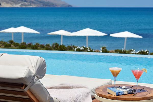 Strandlounge mit Cocktails und Buch am Pool des Giannoulis Grand Bay Beach Resorts