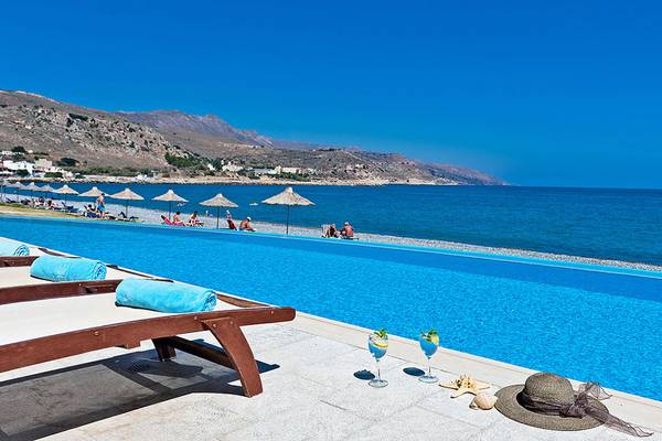 Strandszene mit Infinity-Pool, Sonnenliegen und Ausblick auf das Meer im Giannoulis Grand Bay Beach Resort