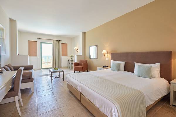 Doppelzimmer im Giannoulis Grand Bay Beach Resort mit Balkon, bequemem Bett und modernen Möbeln.
