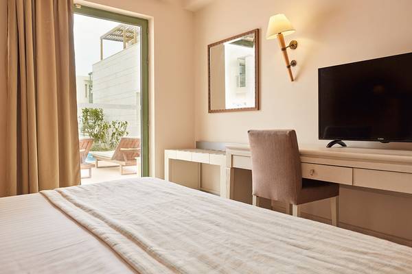 Hotelzimmer im Giannoulis Grand Bay Beach Resort mit Bett, Schreibtisch und Fernseher.