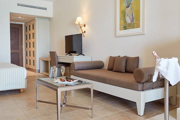 Innenansicht der Suite im Giannoulis Grand Bay Beach Resort mit Fernseher, Schreibtisch und Champagner