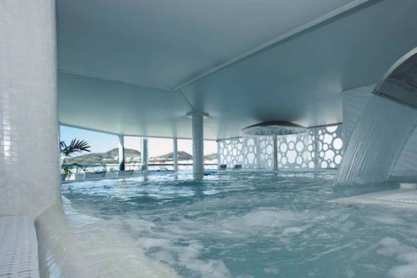 Innenpool des Bull Hotel Reina Isabel & Spa mit Wasserfall und Blick auf die Berge